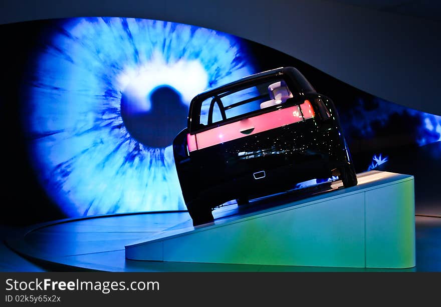 A car displayed in a motor show with eye in the background. A car displayed in a motor show with eye in the background