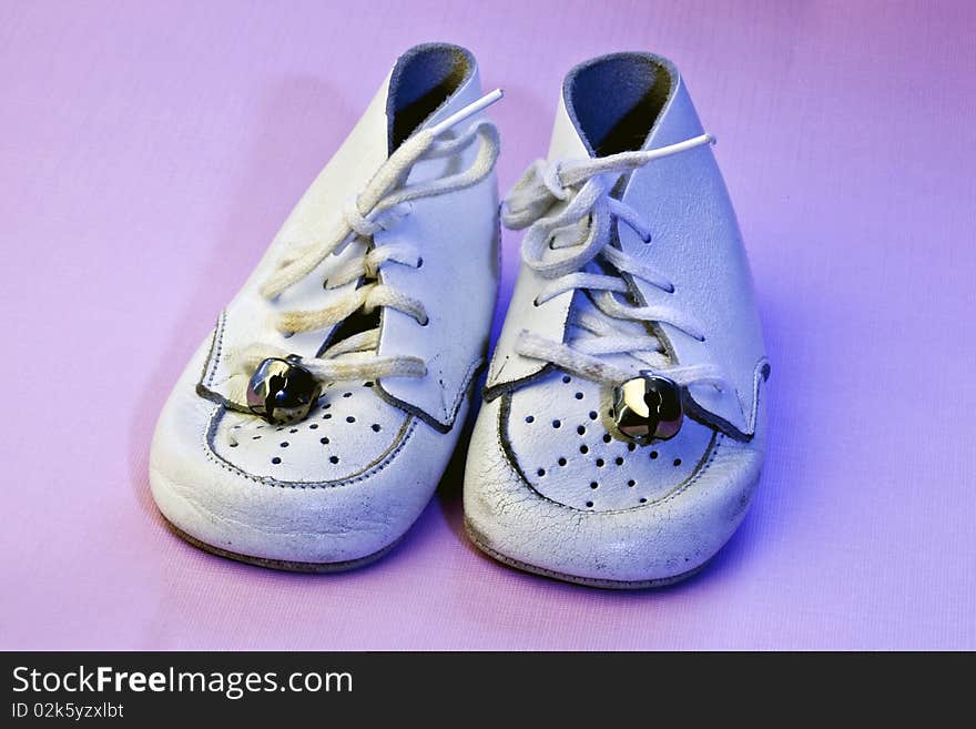 Vintage soft white leather baby shoes on an isolated pink background. Vintage soft white leather baby shoes on an isolated pink background