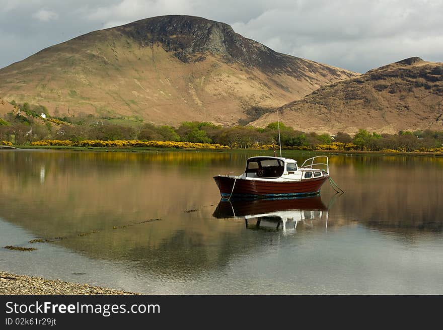 Lochranza loch with mountain reflections and copy  space with boat.