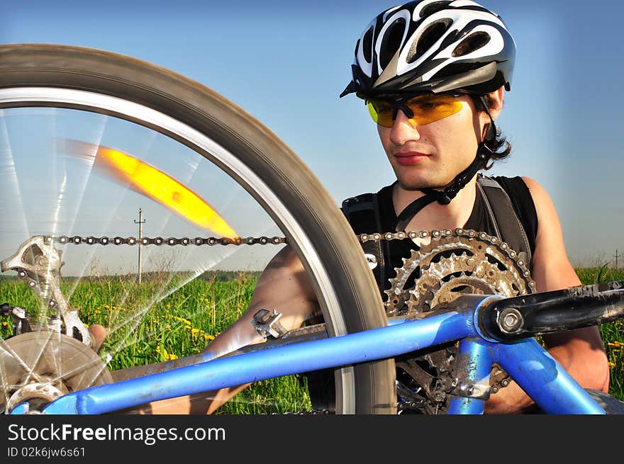 Portrait of a cyclist, making bike tuning. With motion blur on the rear wheel to show the motion