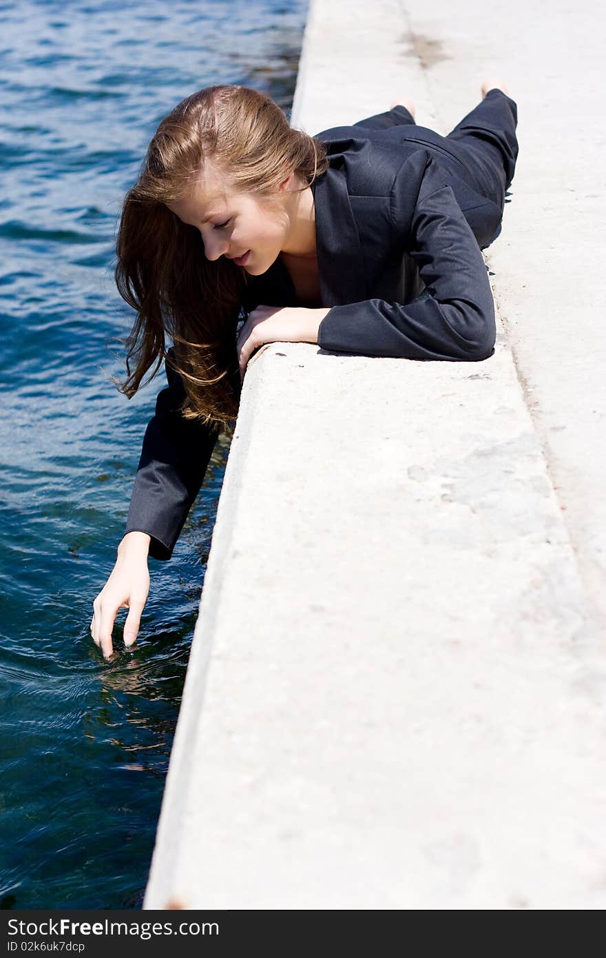 Woman in black suit lying on the border near the water. Woman in black suit lying on the border near the water