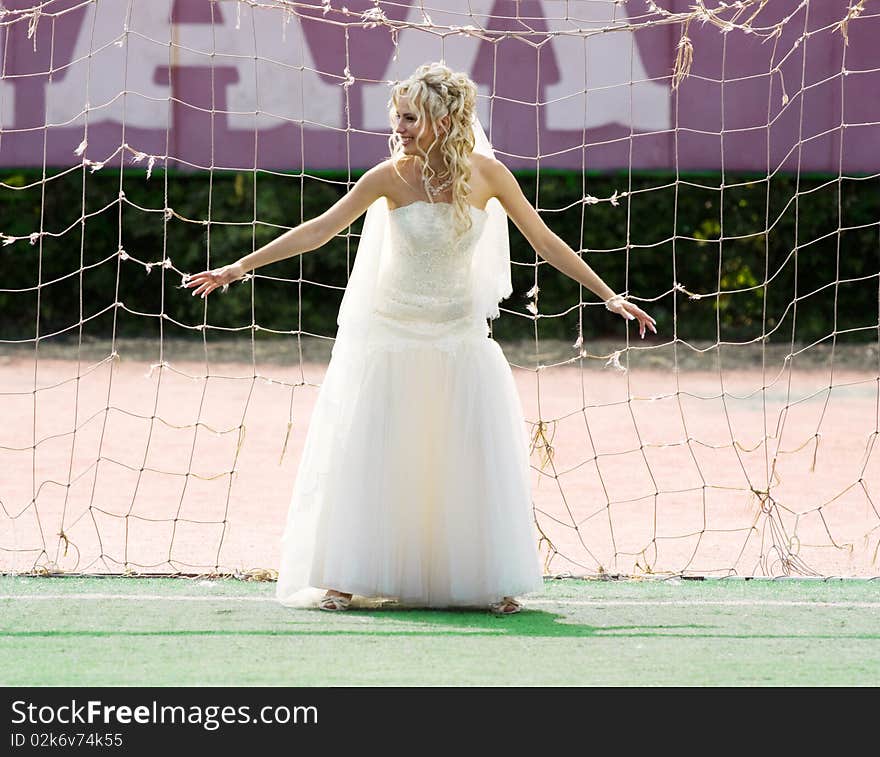 Young beautiful bride standing on the gate with ball. Young beautiful bride standing on the gate with ball