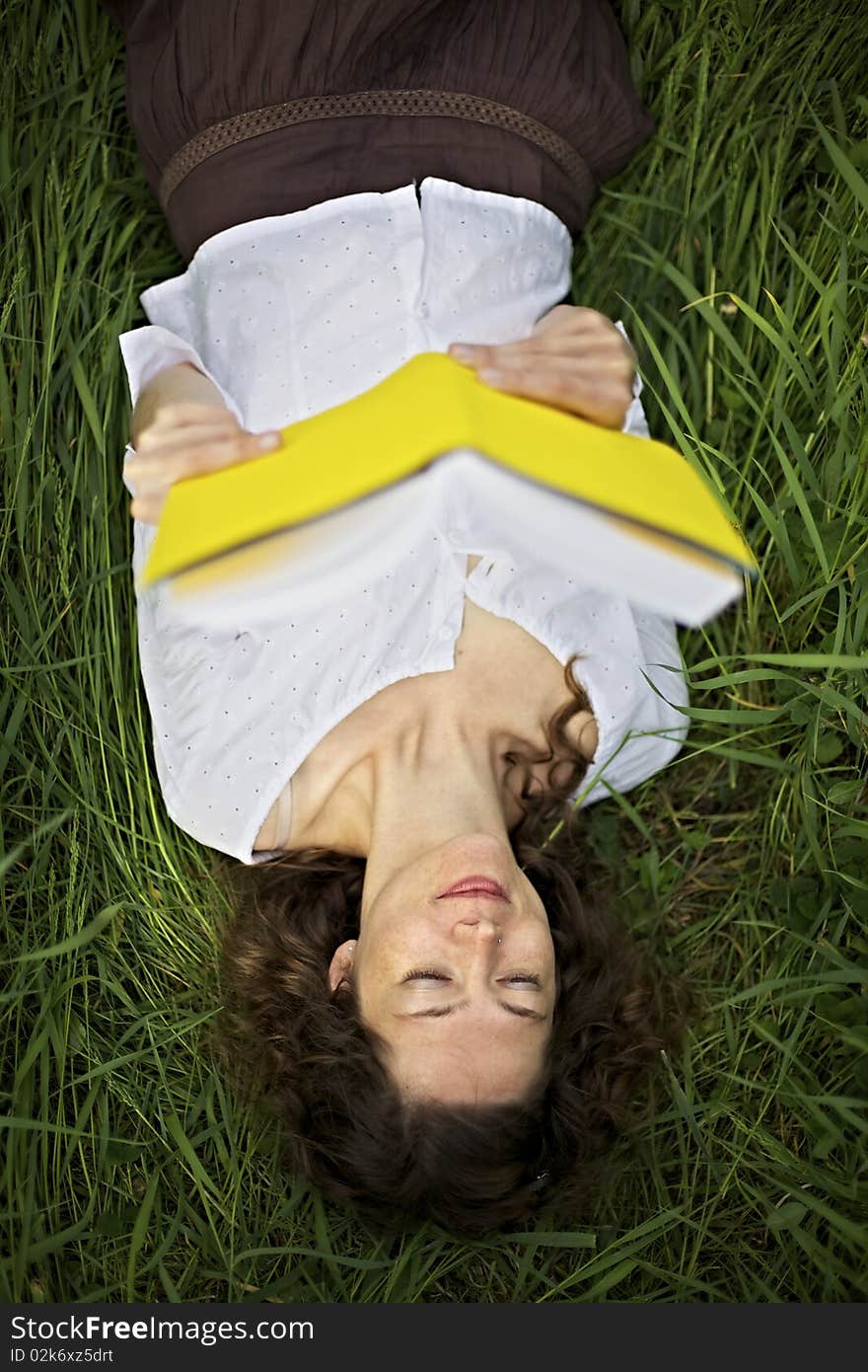 Girl lying in meadow reading