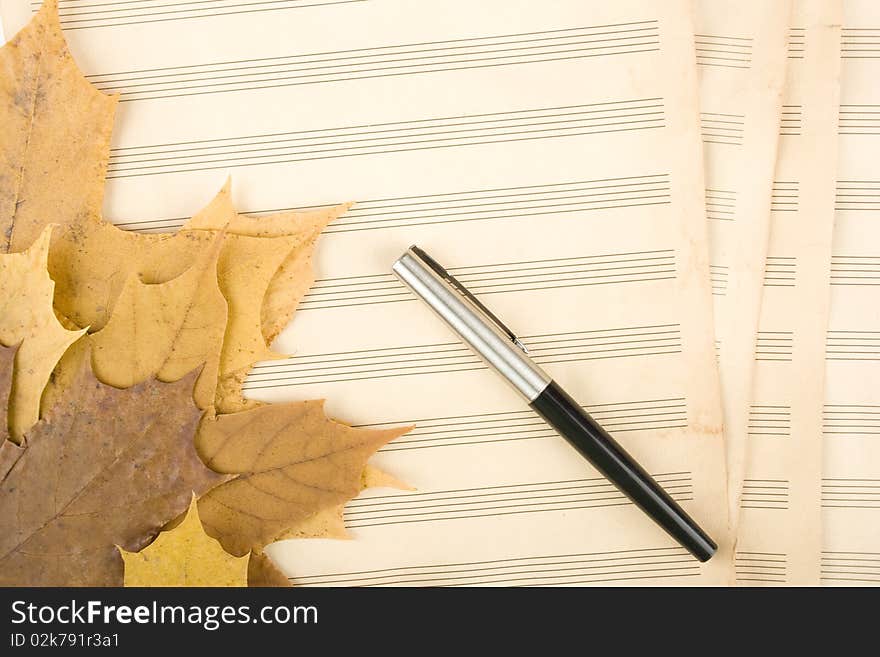 Old sheet music sheet of paper which has a handle and the autumn leaves of maple. Old sheet music sheet of paper which has a handle and the autumn leaves of maple