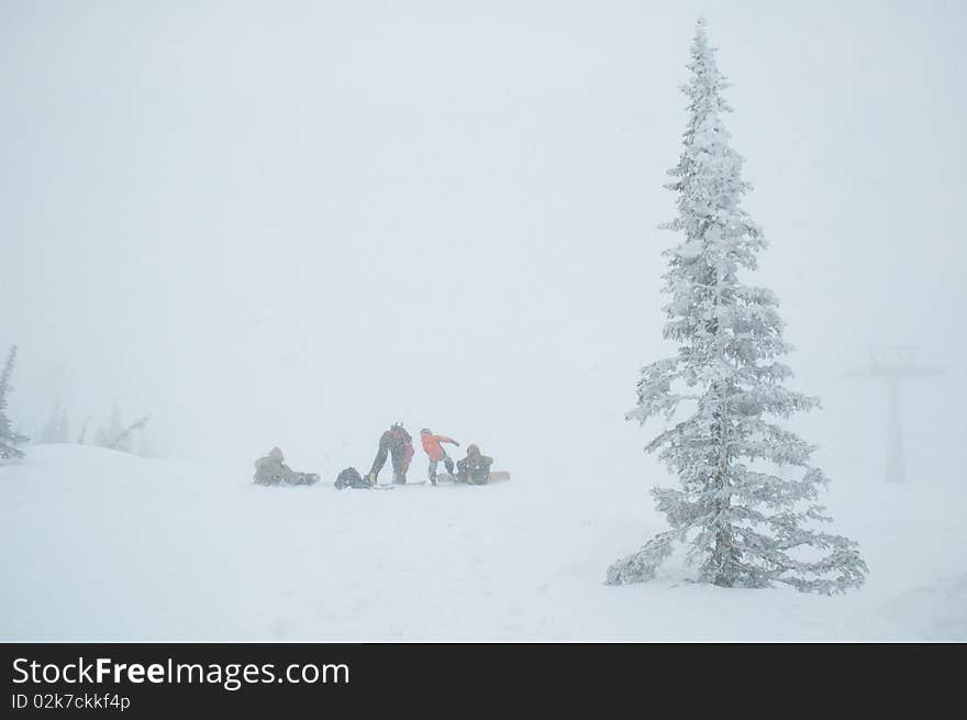 Some persons with snowboards on the edge of white nothing.