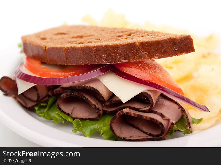 Delicious roast beef sandwich platter with whole wheat bread and potato chips. Delicious roast beef sandwich platter with whole wheat bread and potato chips