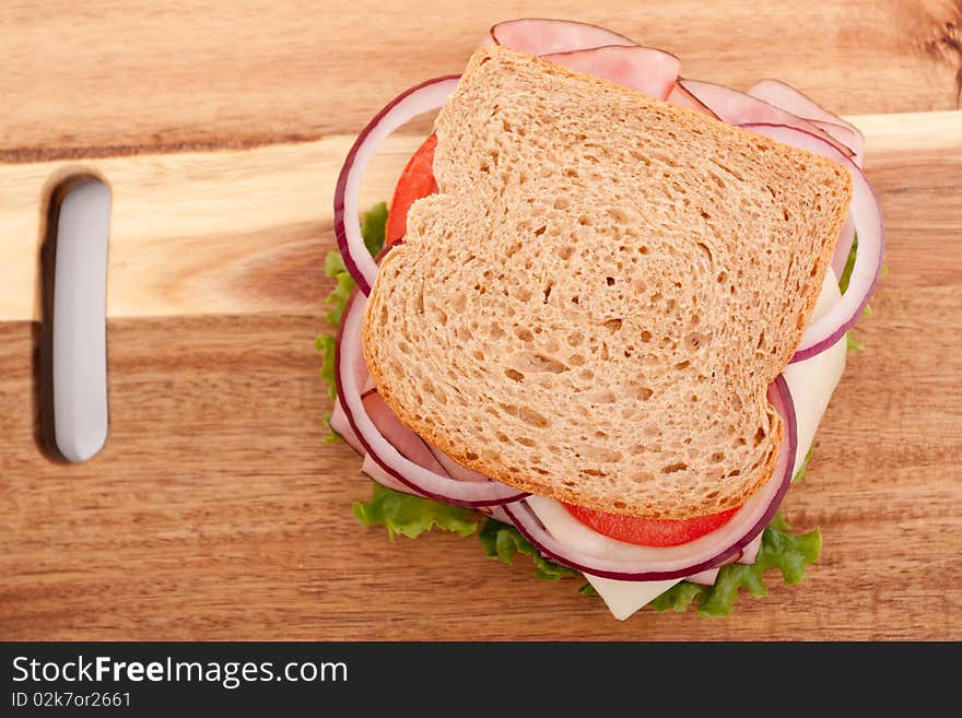 Delicious ham sandwich with whole wheat bread on cutting board. Delicious ham sandwich with whole wheat bread on cutting board