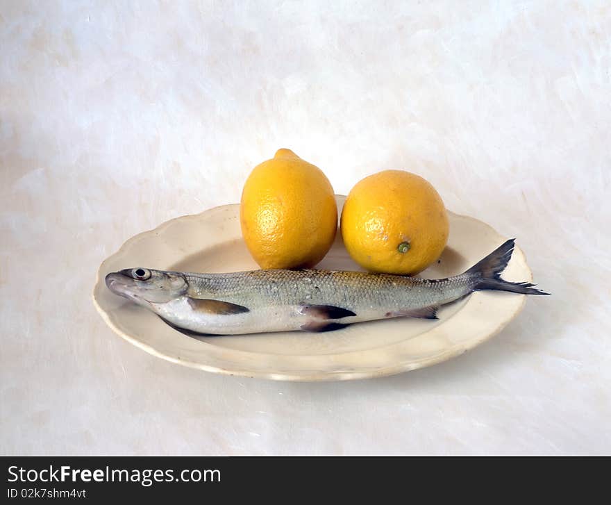 Fish with lemon on plate isolated on painted background