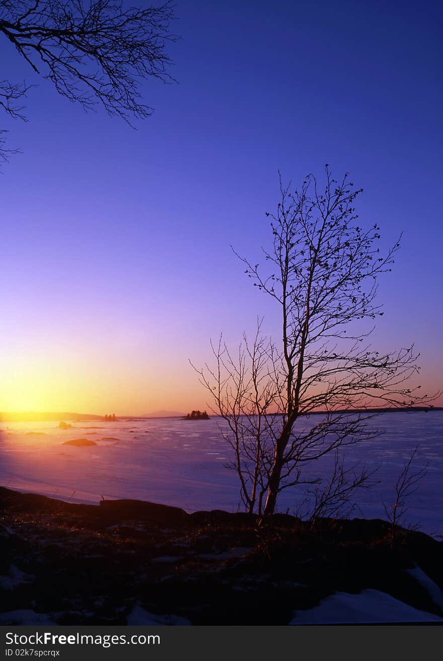 Beautiful winter landscape of snowy lake at sunset