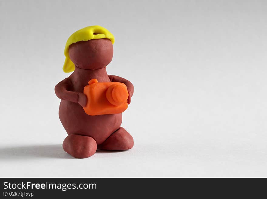 Plasticine man with photo camera over grey background