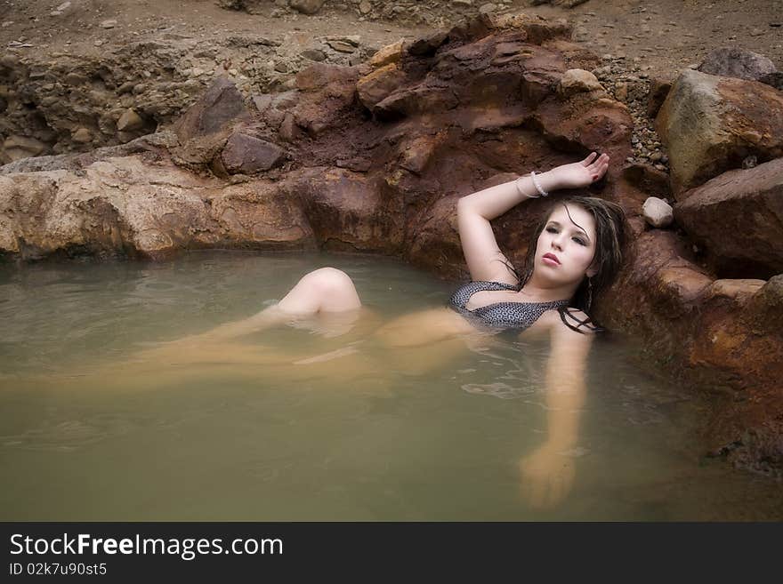 A woman is in the water with her hand over her head. A woman is in the water with her hand over her head.