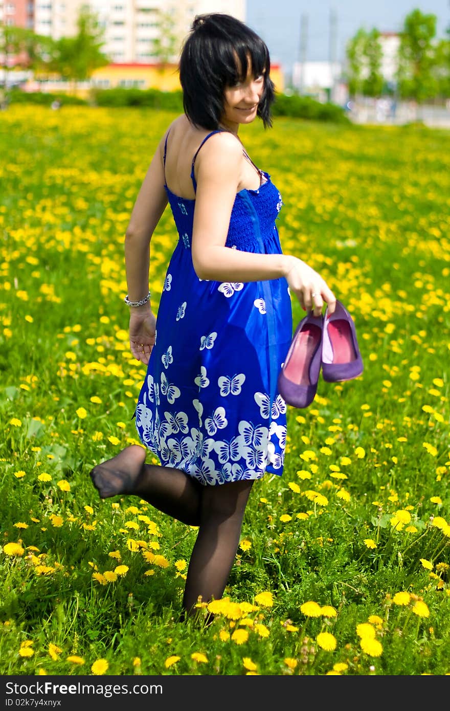 Summer girl in a blue dress against a background of green grass. Summer girl in a blue dress against a background of green grass