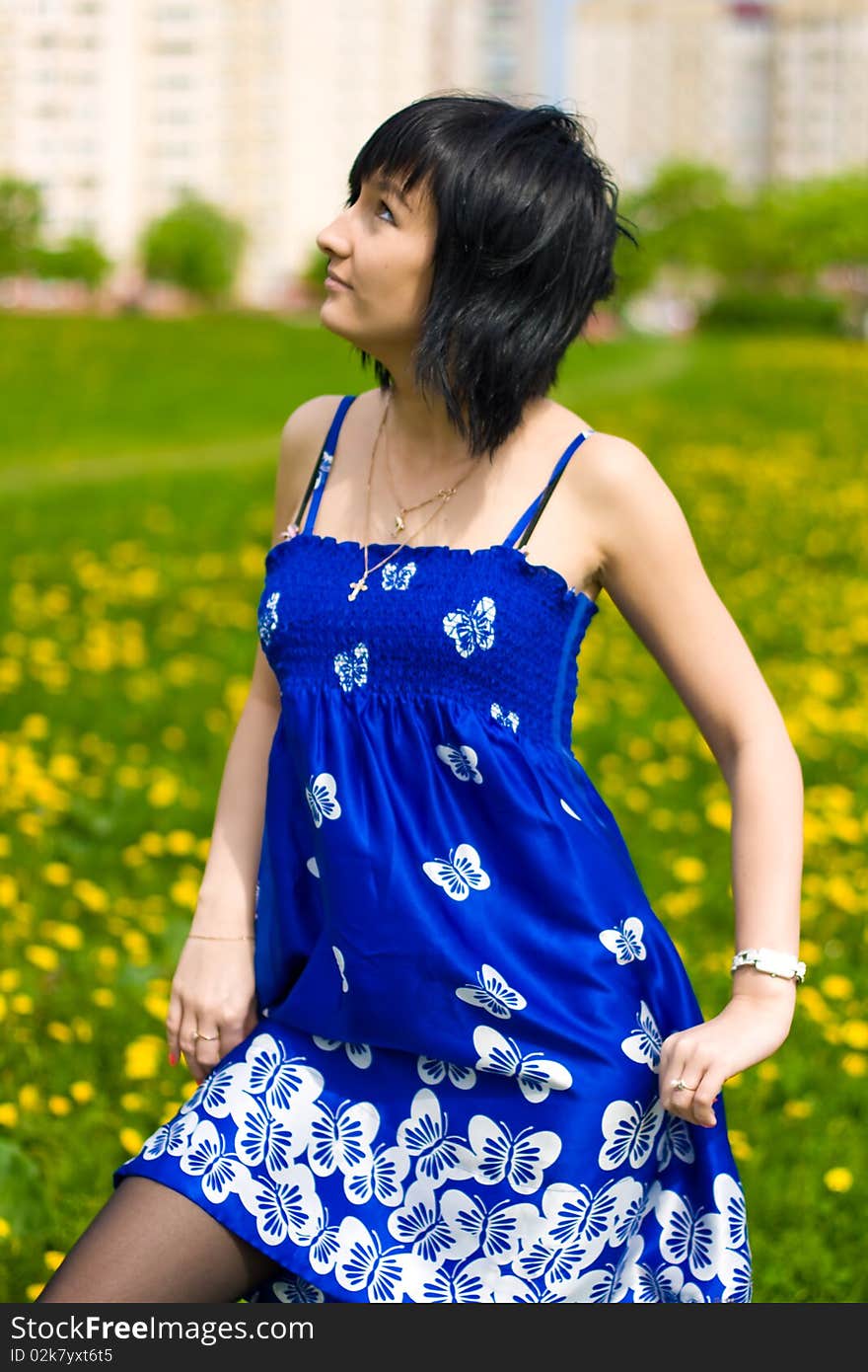 Summer girl in a blue dress against a background of green grass. Summer girl in a blue dress against a background of green grass