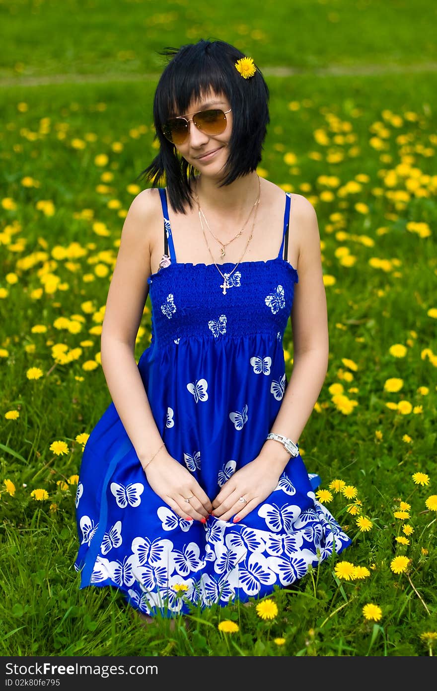 Summer girl in a blue dress against a background of green grass. Summer girl in a blue dress against a background of green grass