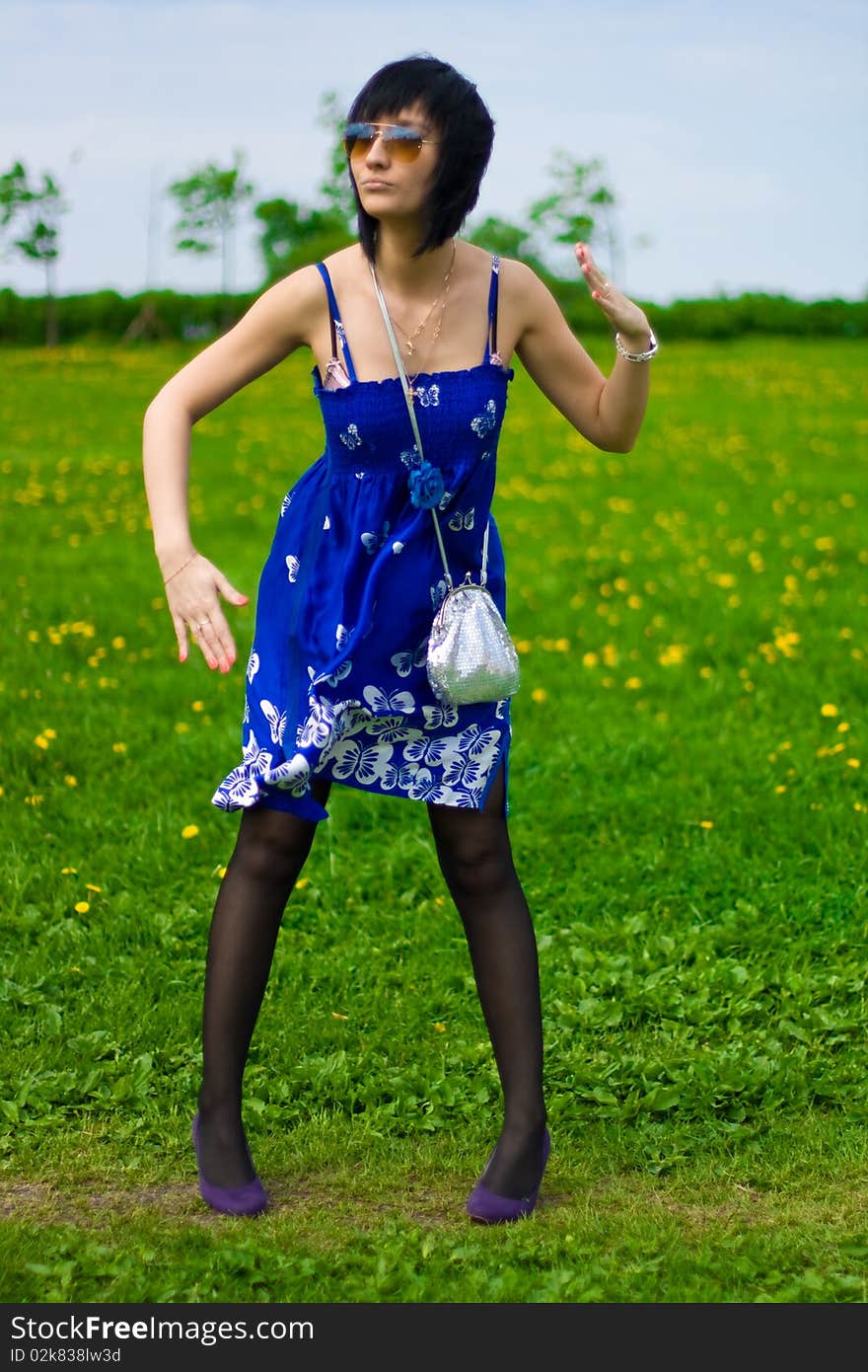 Summer girl in a blue dress against a background of green grass. Summer girl in a blue dress against a background of green grass