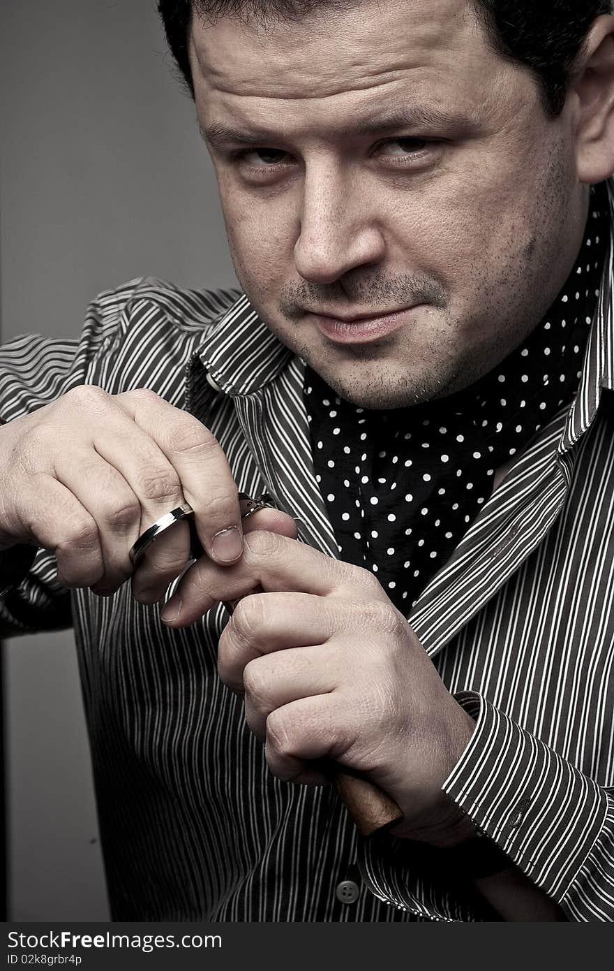 Handsome man cutting a cigar with a cigar clipper.