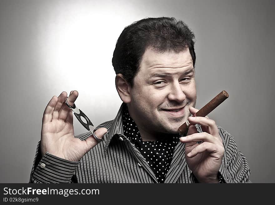 Handsome man holding a cigar and a cigar clipper smiling to the viewer. Handsome man holding a cigar and a cigar clipper smiling to the viewer.