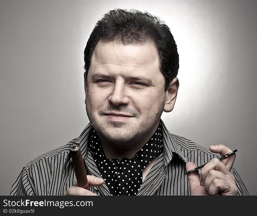 Handsome man holding a cigar and a cigar clipper. Handsome man holding a cigar and a cigar clipper.