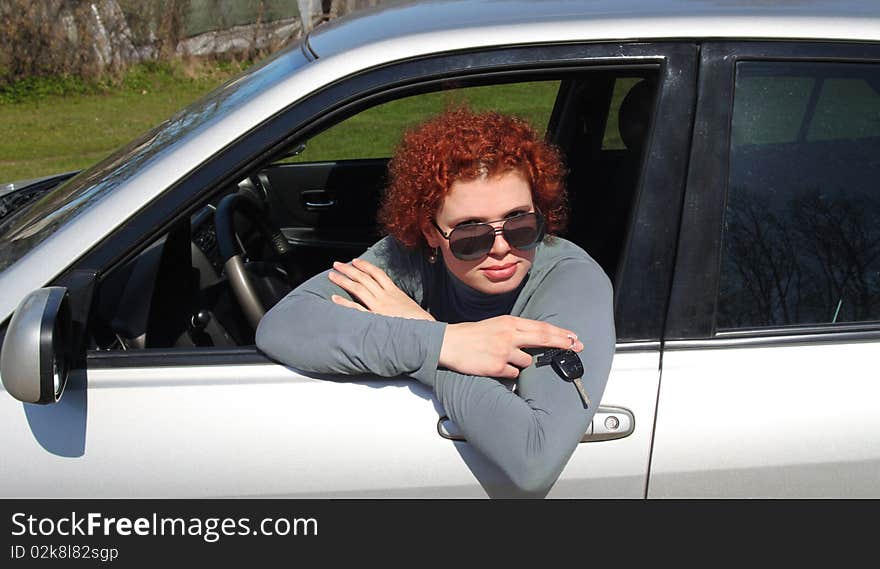 Young woman sitting in a car and holding in hand keys to her new car .