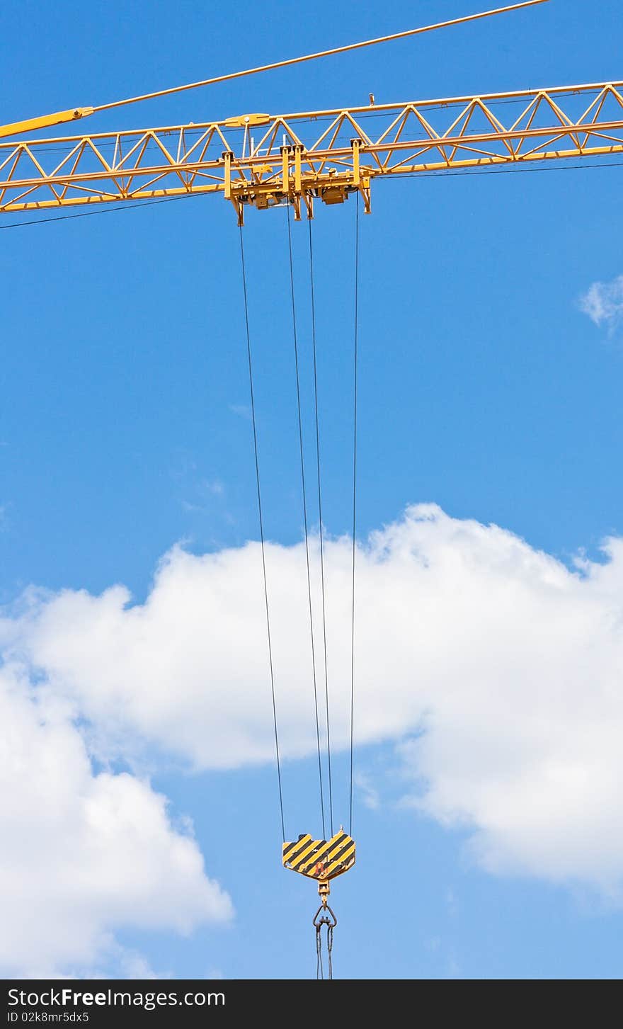 Crane hook over blue sky with clouds