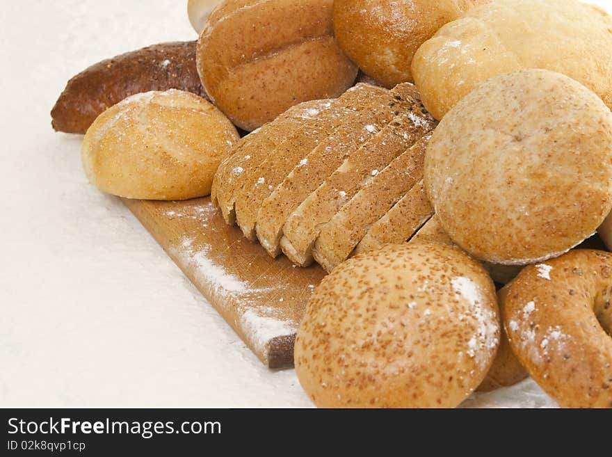 Different types of bread on a wooden board sprinkled with flour