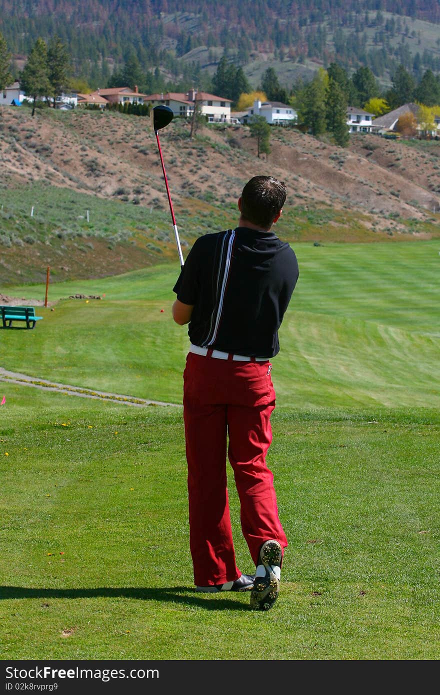 Young male golfer following his drive shot. Young male golfer following his drive shot