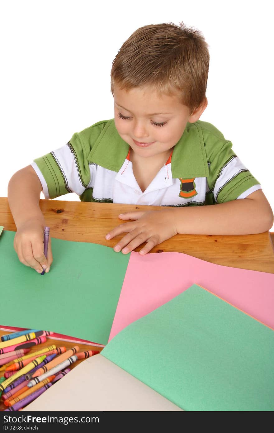 Young blond boy writing with crayons on colored paper. Young blond boy writing with crayons on colored paper