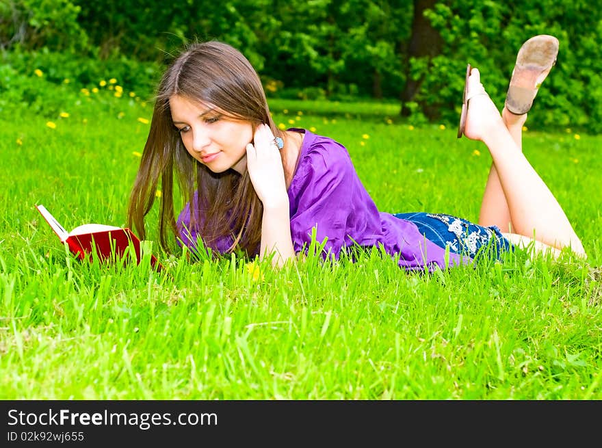 Young smiling woman reading on the grass. Young smiling woman reading on the grass