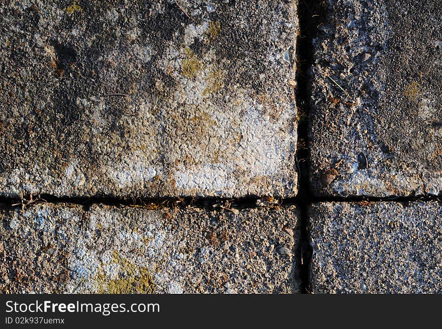 A Gray brick surface texture that is worn and old