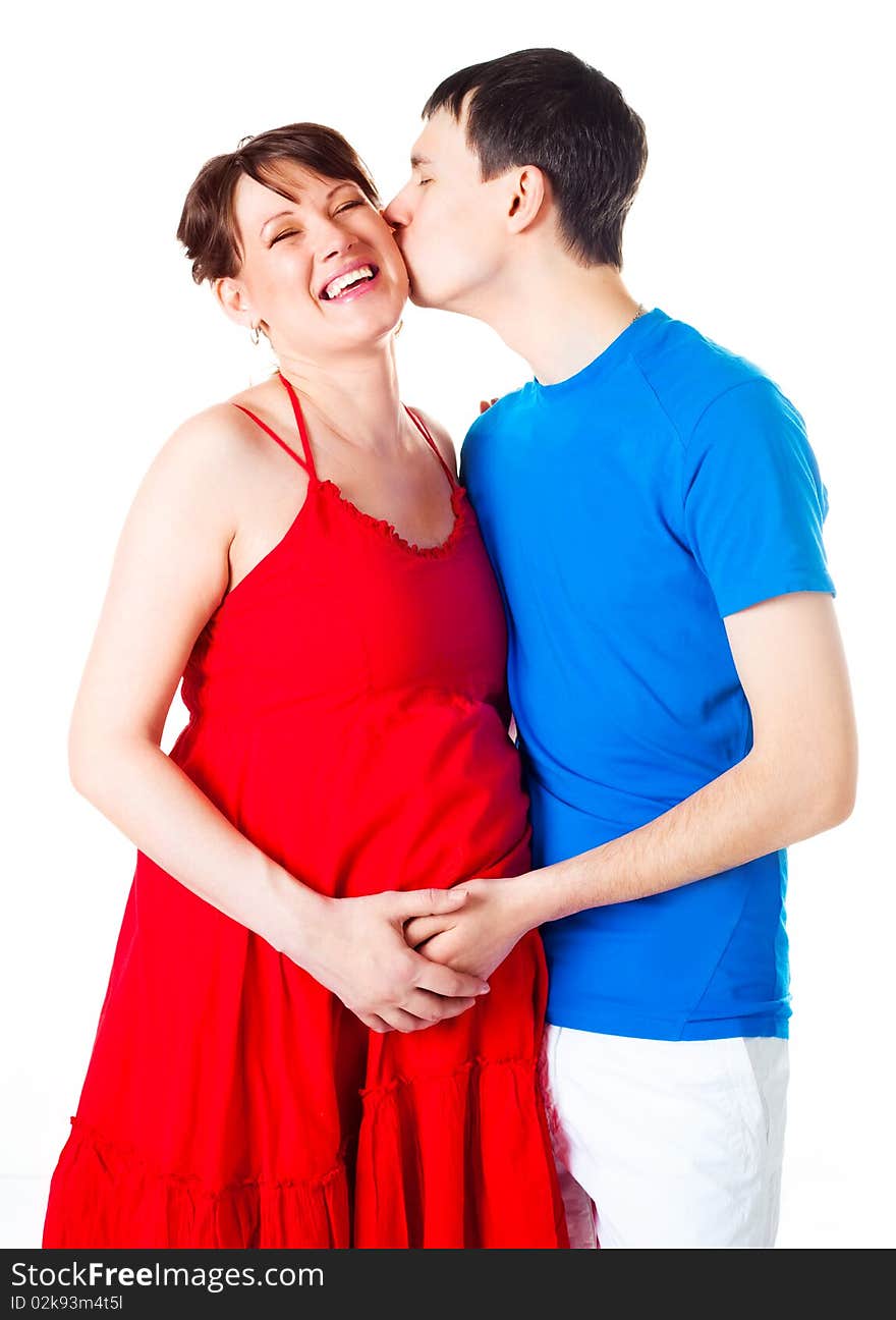 Young happy pregnant woman and her husband embracing and kissing