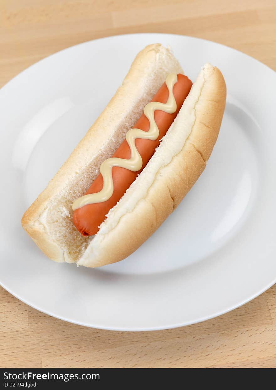 A hotdog with mustard sauce on a kitchen bench. A hotdog with mustard sauce on a kitchen bench