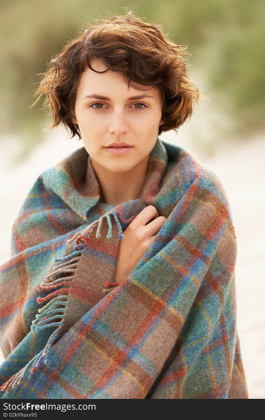 Woman Standing In Sand Dunes Wrapped In Blanket