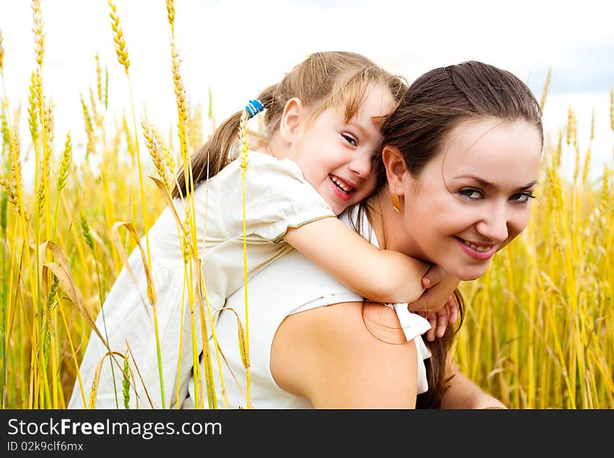 Beautiful young mother and her daughter at the wheat field on a sunny day. Beautiful young mother and her daughter at the wheat field on a sunny day