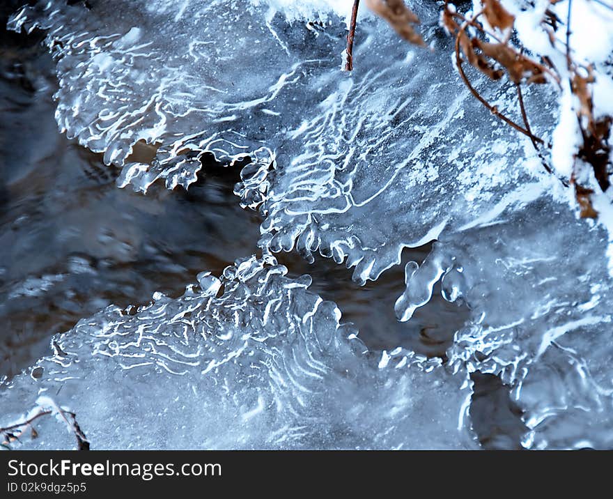 Ice crystals over flowing winter stream closeup