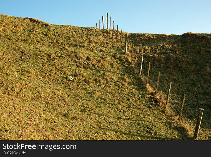 Farm fence, disappearing over hill. Farm fence, disappearing over hill.