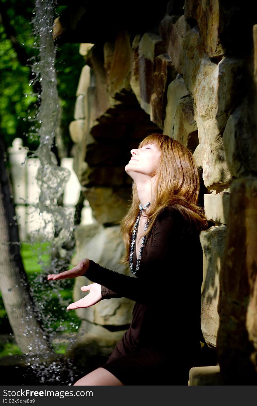 A beautiful girl spreads hand to the waterfall. A beautiful girl spreads hand to the waterfall