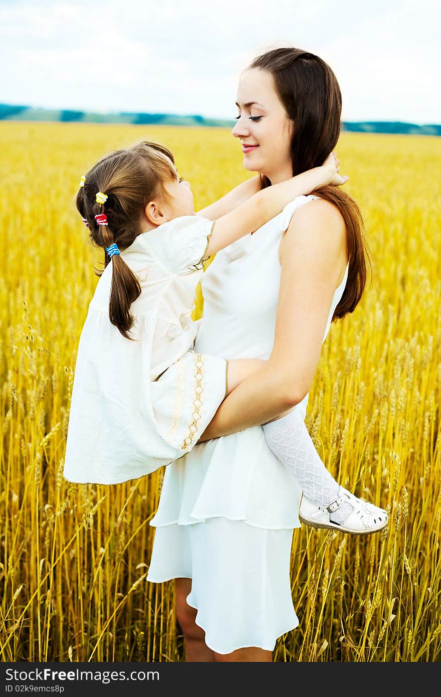 Beautiful young mother and her daughter at the wheat field on a sunny day. Beautiful young mother and her daughter at the wheat field on a sunny day