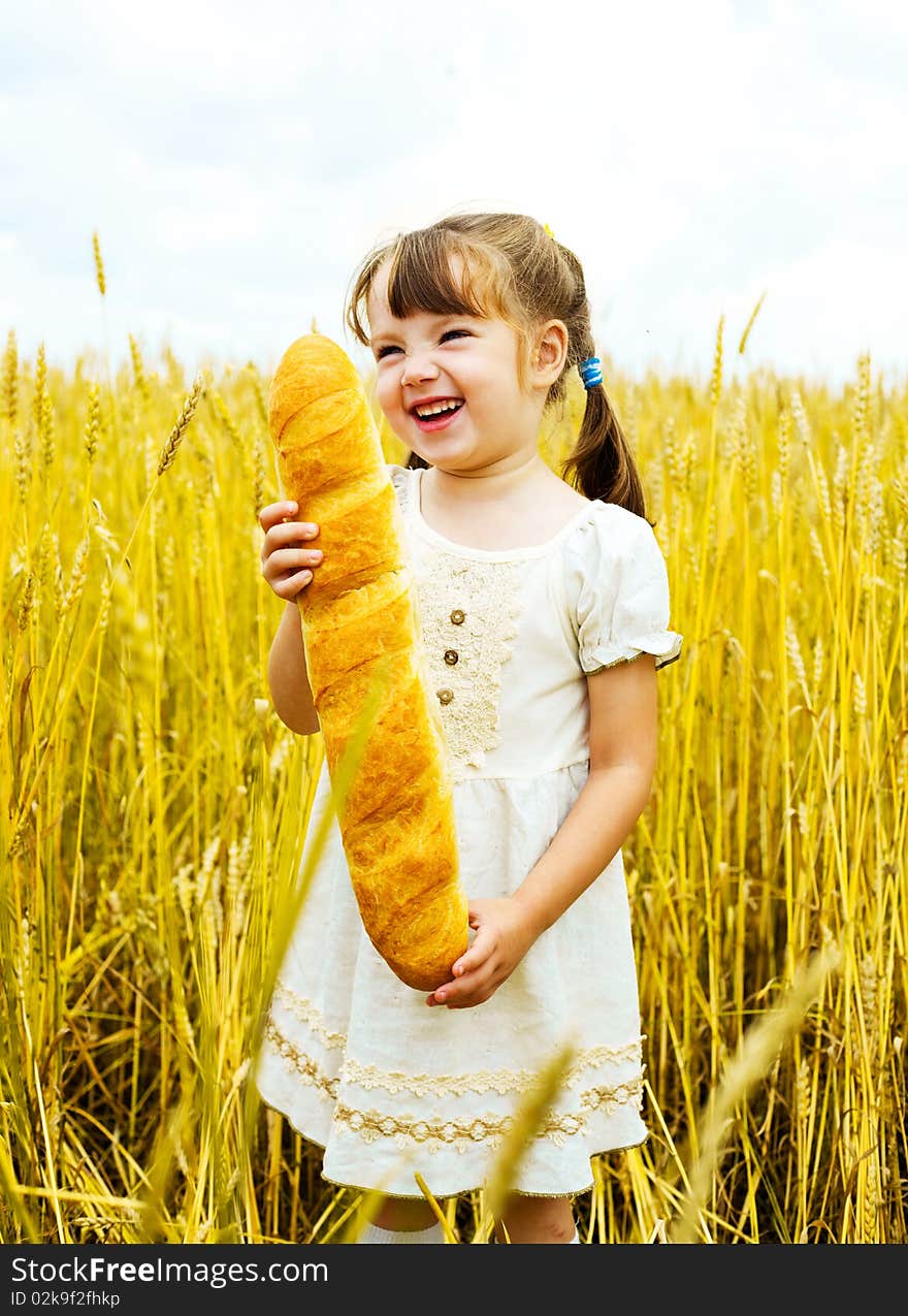 Happy cute little girl in the wheat field with a long loaf. Happy cute little girl in the wheat field with a long loaf