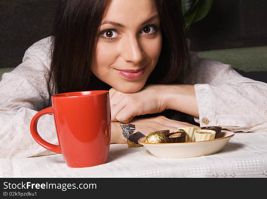 Beautiful lady drinking tea with chocolate candies