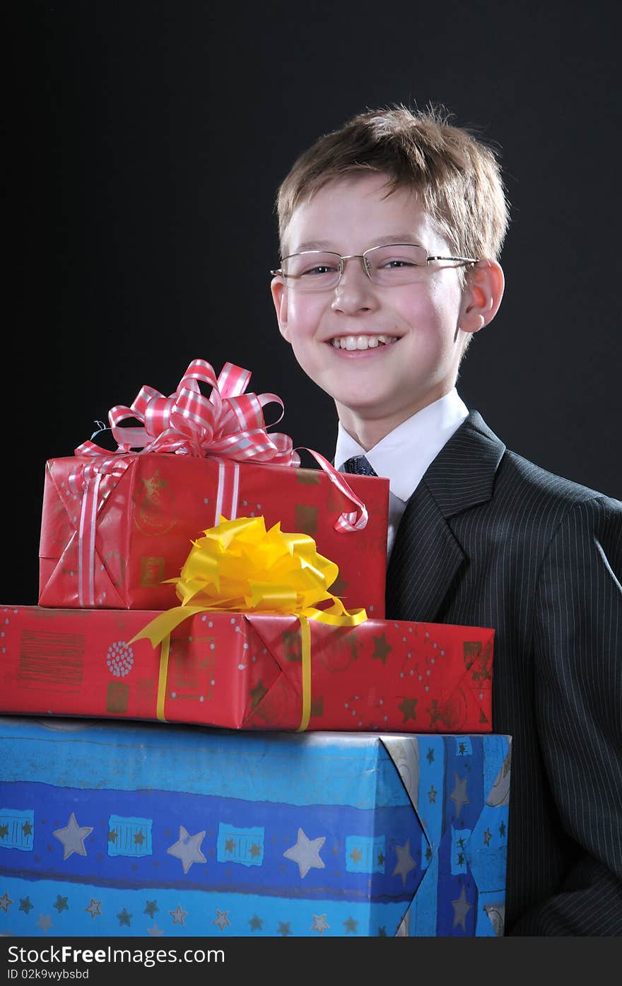 Boy in a dark suit gets on the hip bright boxes with gifts. Boy in a dark suit gets on the hip bright boxes with gifts