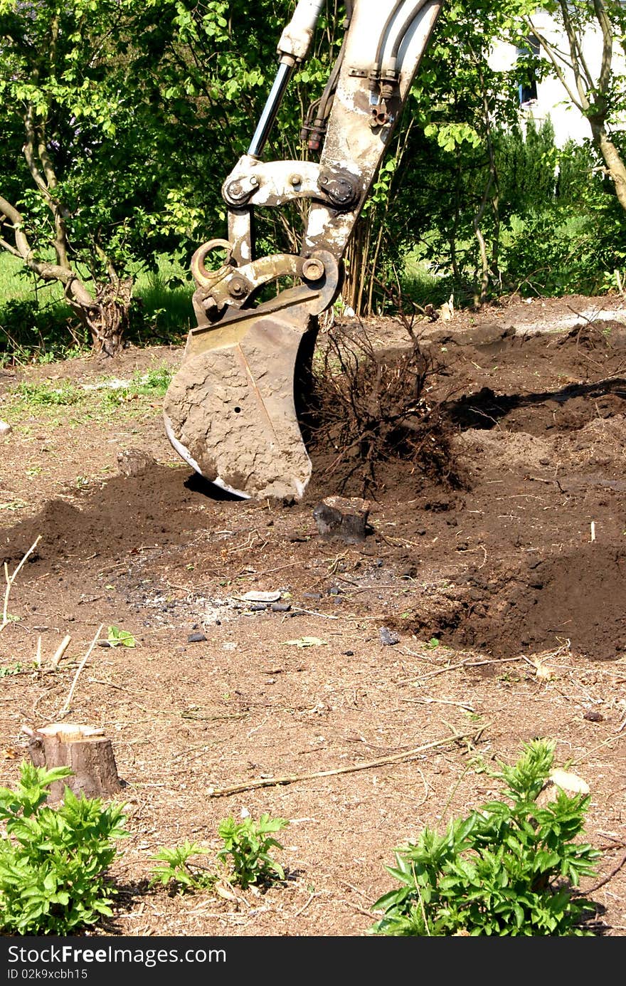 An excavator working in a garden. An excavator working in a garden