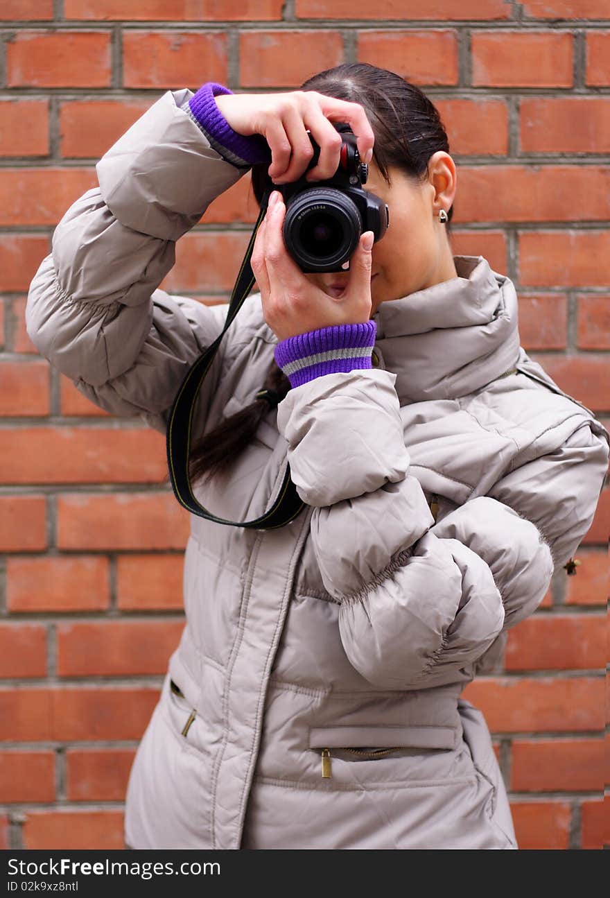 Woman photographer on the background of a brick wall