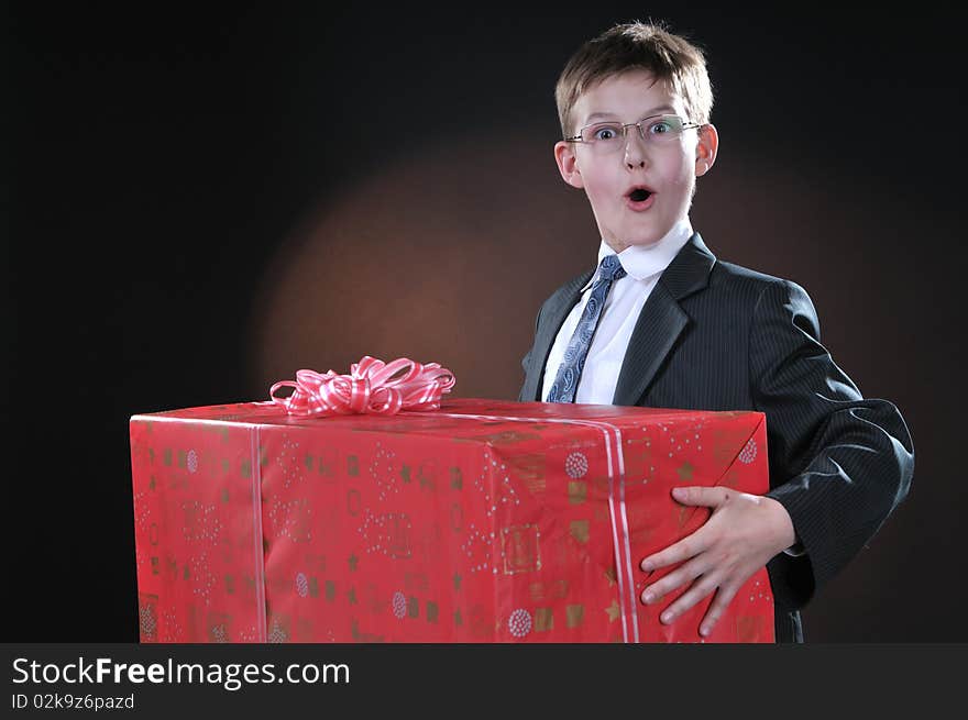 Boy in a dark suit gets on the hip bright boxes with gifts. Boy in a dark suit gets on the hip bright boxes with gifts