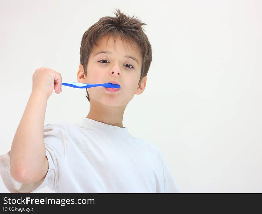 A handsome boy cleaning his teeth looking at the camera isolated on a white background. A handsome boy cleaning his teeth looking at the camera isolated on a white background