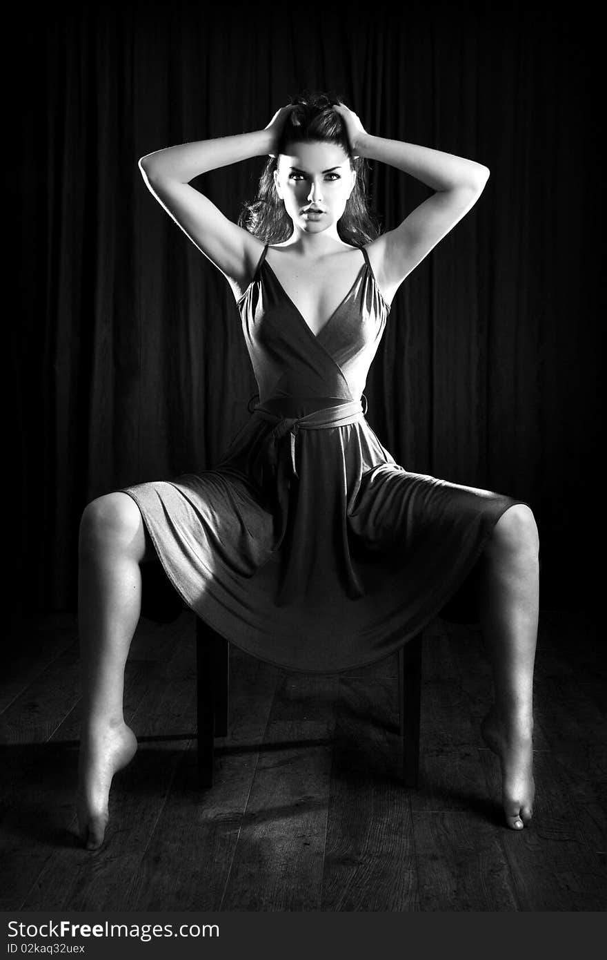 A glamorous young woman sitting on a stool and looking to the camera. A glamorous young woman sitting on a stool and looking to the camera.