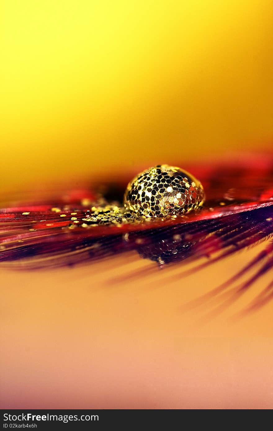 Waterdrop sitting on top of a feather, with some glitter. Waterdrop sitting on top of a feather, with some glitter.