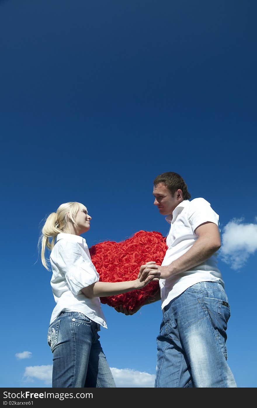 Couple of young people, loving boy and girl holding hands in the heart of roses. Couple of young people, loving boy and girl holding hands in the heart of roses