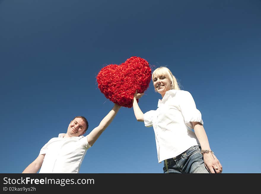 Couple of young people, loving boy and girl holding hands in the heart of roses. Couple of young people, loving boy and girl holding hands in the heart of roses