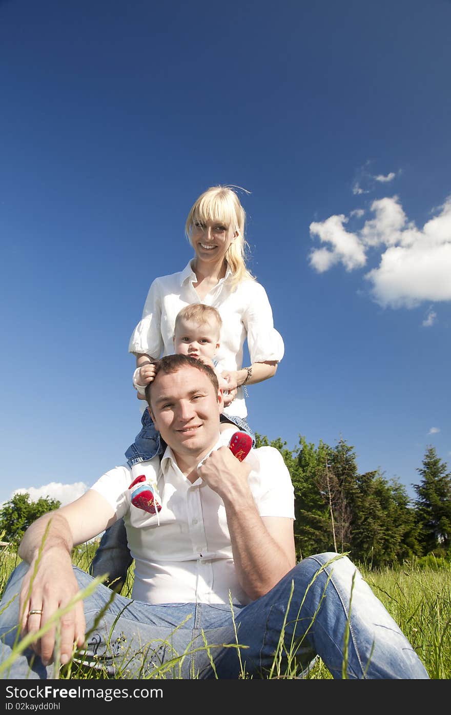 Happy young family, father, mother and child in the park on the green grass