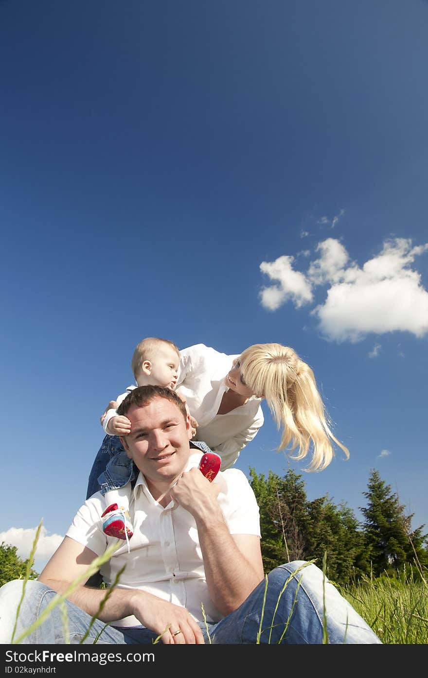 Happy young family, father, mother and child in the park on the green grass